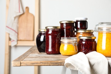 Jars with different jams on wooden table