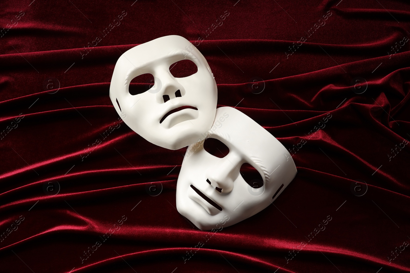 Photo of Theater arts. White masks on red fabric, above view