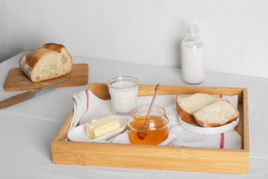 Milk, honey and bread served for breakfast on table indoors
