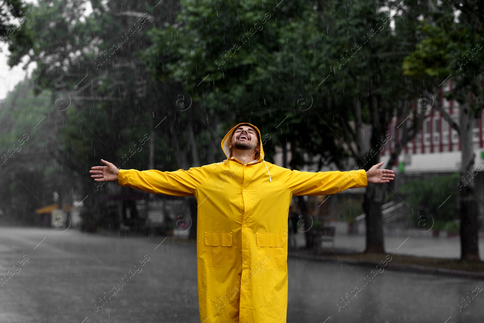 Photo of Happy young man in bright coat outdoors on rainy day