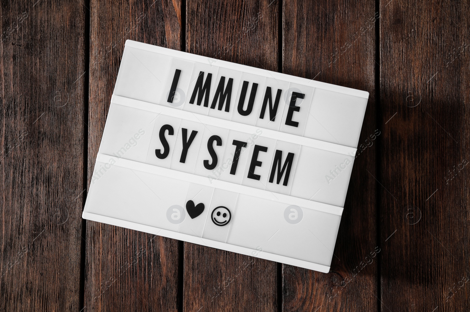 Photo of Lightbox with words Immune System on wooden table, top view