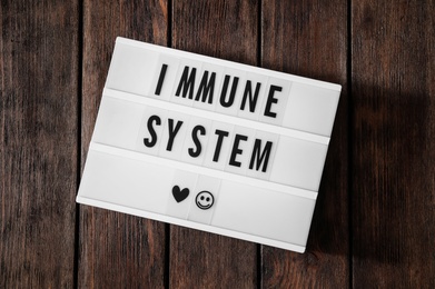 Photo of Lightbox with words Immune System on wooden table, top view