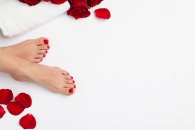 Woman with stylish red toenails after pedicure procedure and rose flowers on white background, top view. Space for text