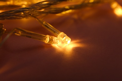 Glowing Christmas lights on violet background, closeup view