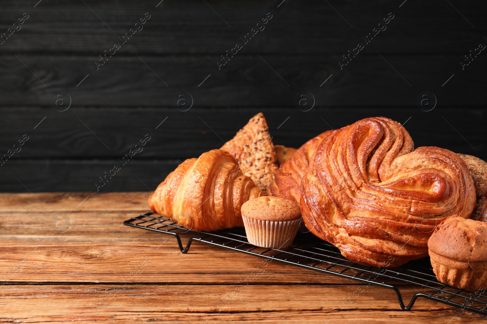 Photo of Different tasty freshly baked pastries on wooden table, space for text