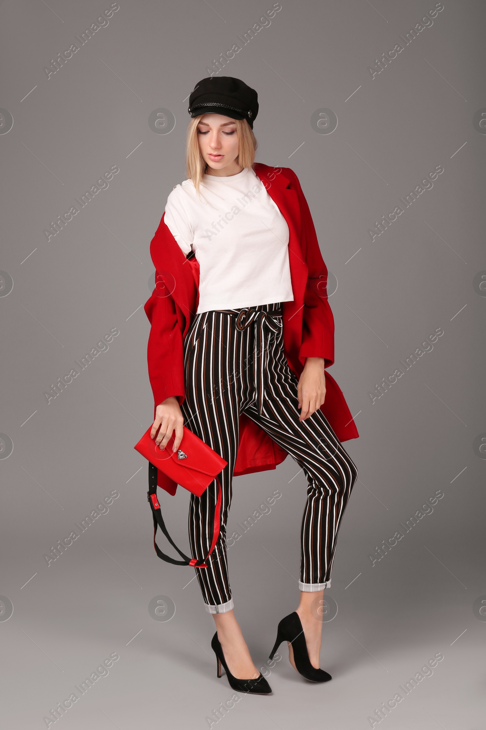 Photo of Young stylish woman in trendy shoes with bum bag on grey background