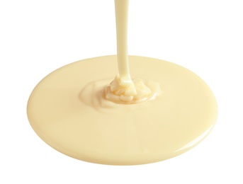 Photo of Tasty pouring condensed milk on white background. Dairy product