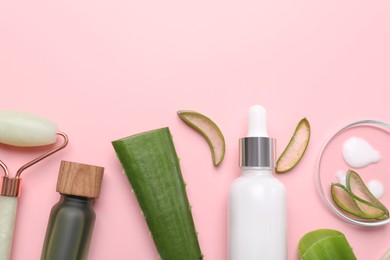 Cosmetic products, cut aloe leaves and face roller on pink background, flat lay. Space for text