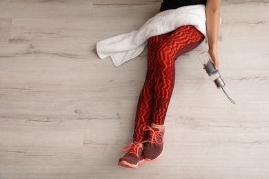 Photo of Woman in sportswear with bottle of water and towel sitting on floor indoors, top view. Space for text