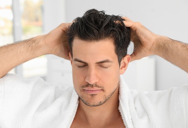 Photo of Handsome man applying hair conditioner in bathroom