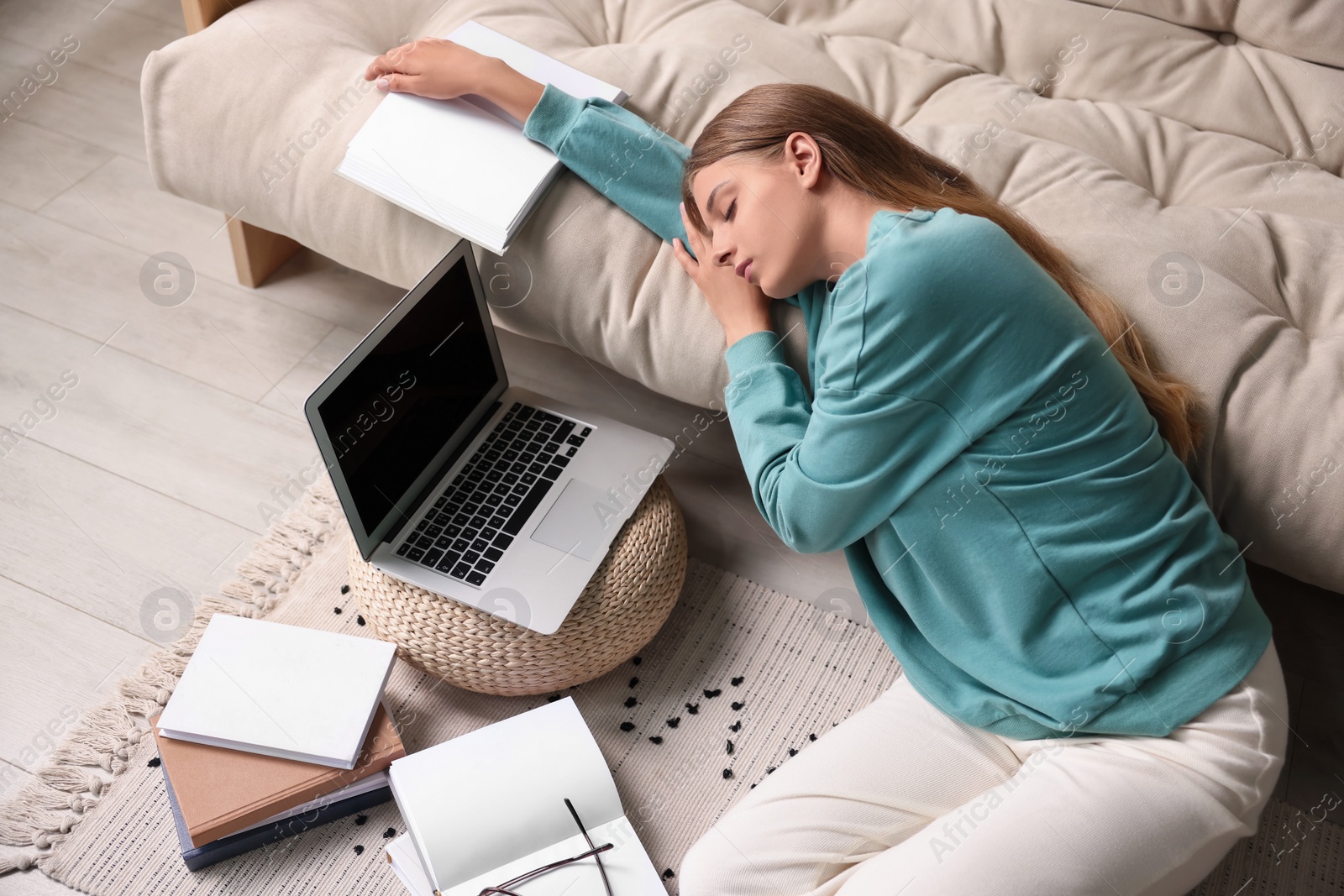 Photo of Young tired woman sleeping near couch at home