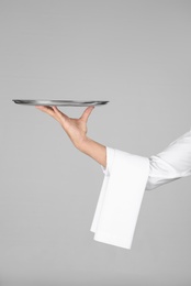 Photo of Waiter holding metal tray on grey background