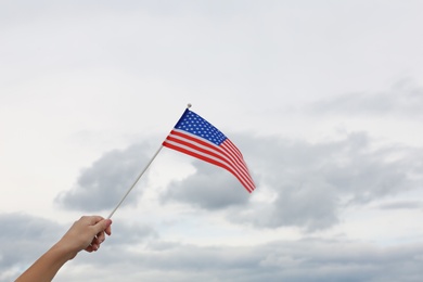 Woman holding small American flag outdoors, closeup. Space for text