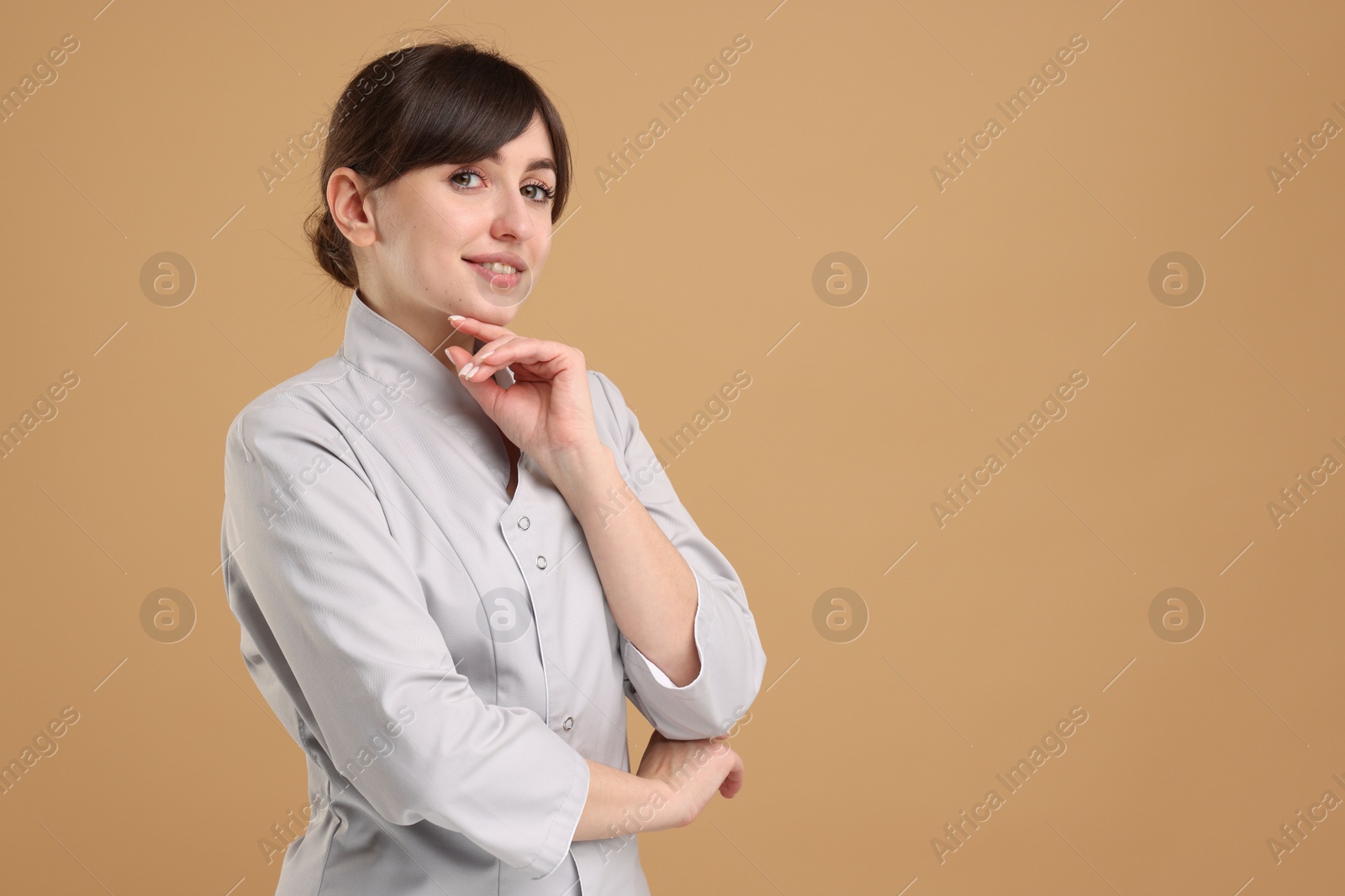 Photo of Cosmetologist in medical uniform on beige background, space for text