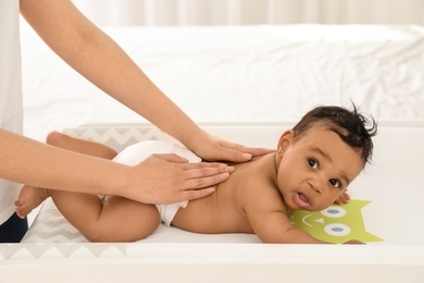 Photo of Mother and her cute child on changing table. Baby massage and exercises