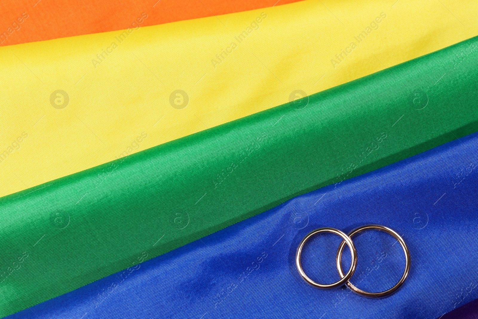 Photo of Wedding rings on rainbow LGBT flag, top view