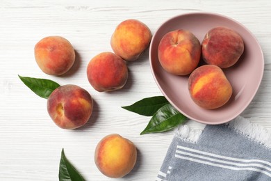 Photo of Many whole fresh ripe peaches and green leaves on white wooden table, flat lay