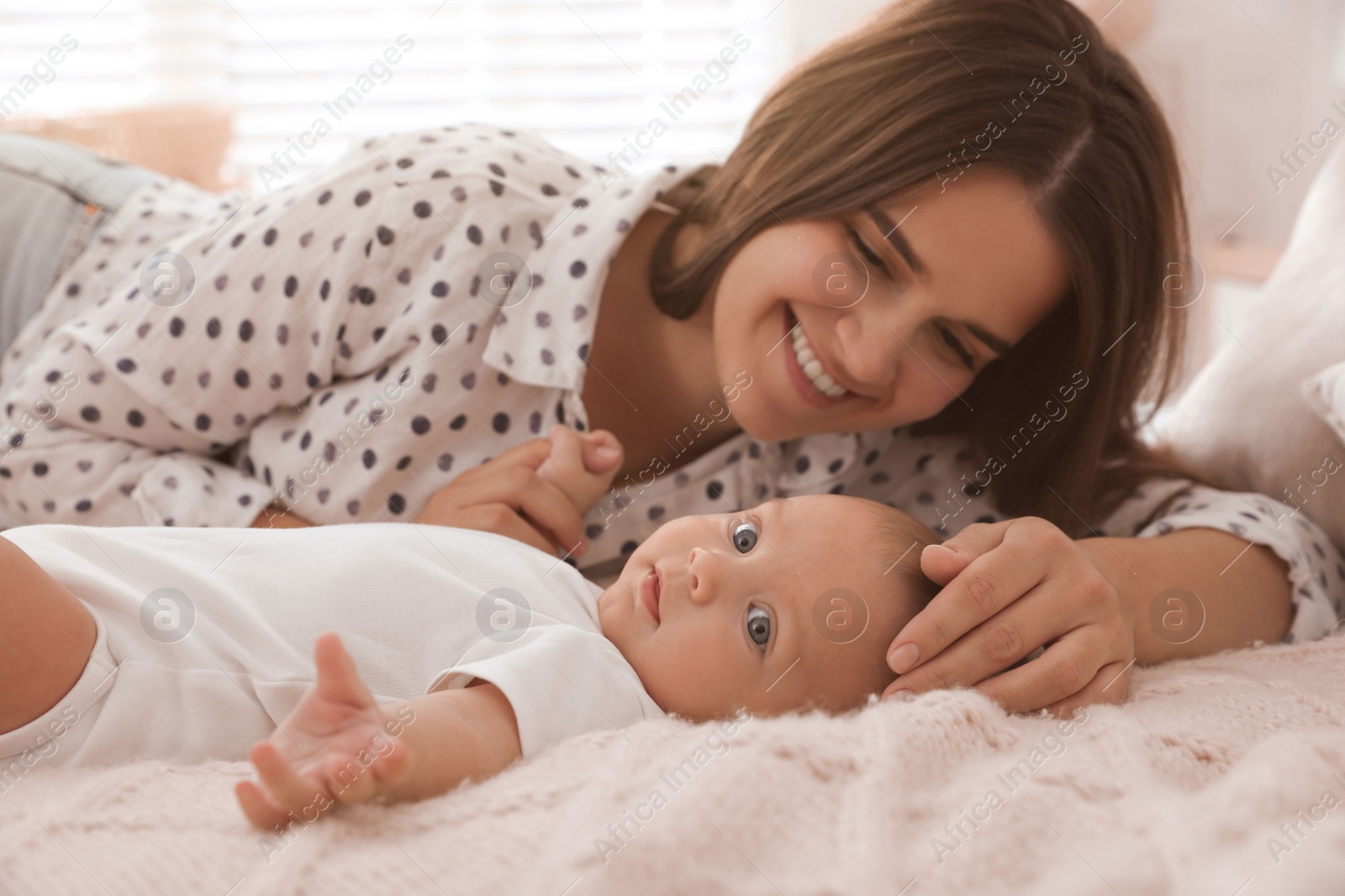 Photo of Mother with her cute baby on bed at home