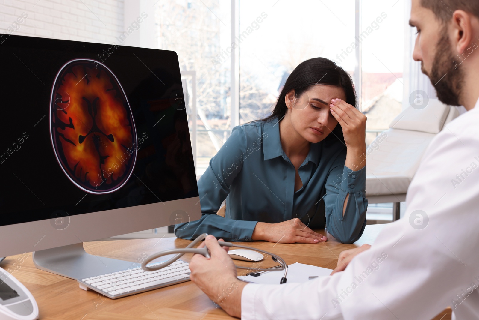 Photo of Neurologist consulting young patient at table in clinic