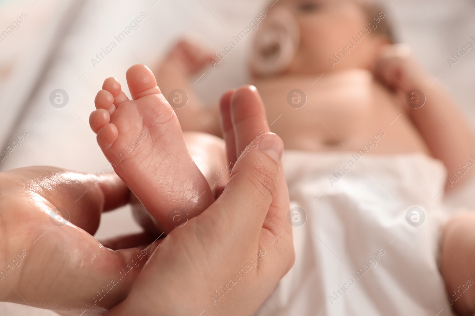 Photo of Mother massaging her cute baby with oil, closeup