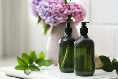 Photo of Soap dispensers and beautiful bouquet on table. Space for text