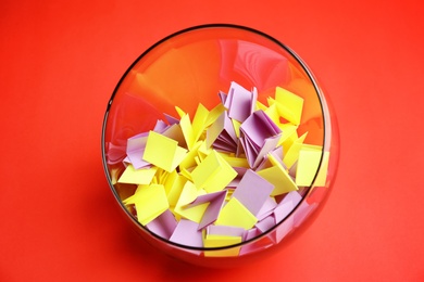Photo of Paper pieces for lottery in glass vase on color background