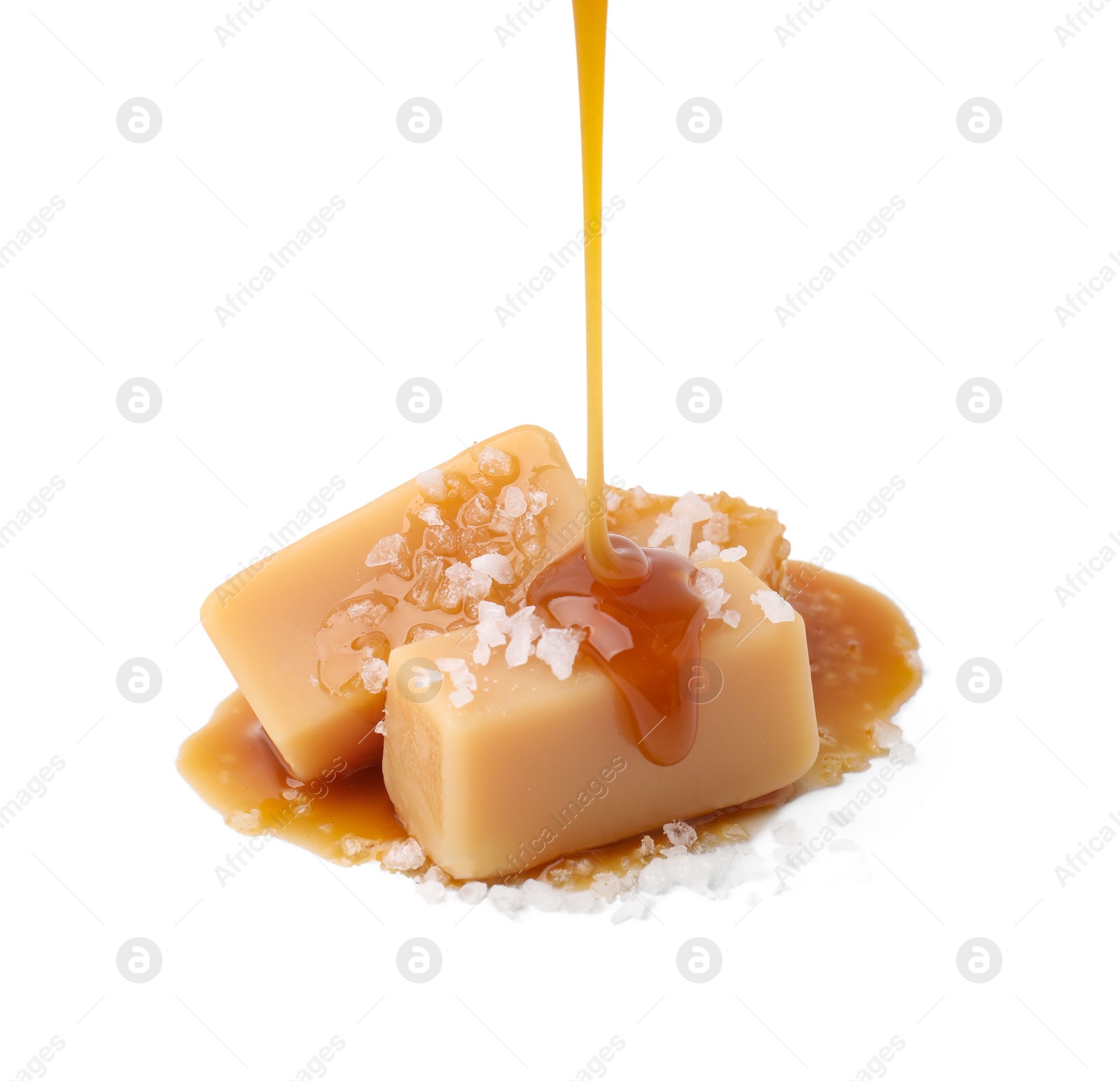 Photo of Pouring delicious salted caramel on candies isolated on white