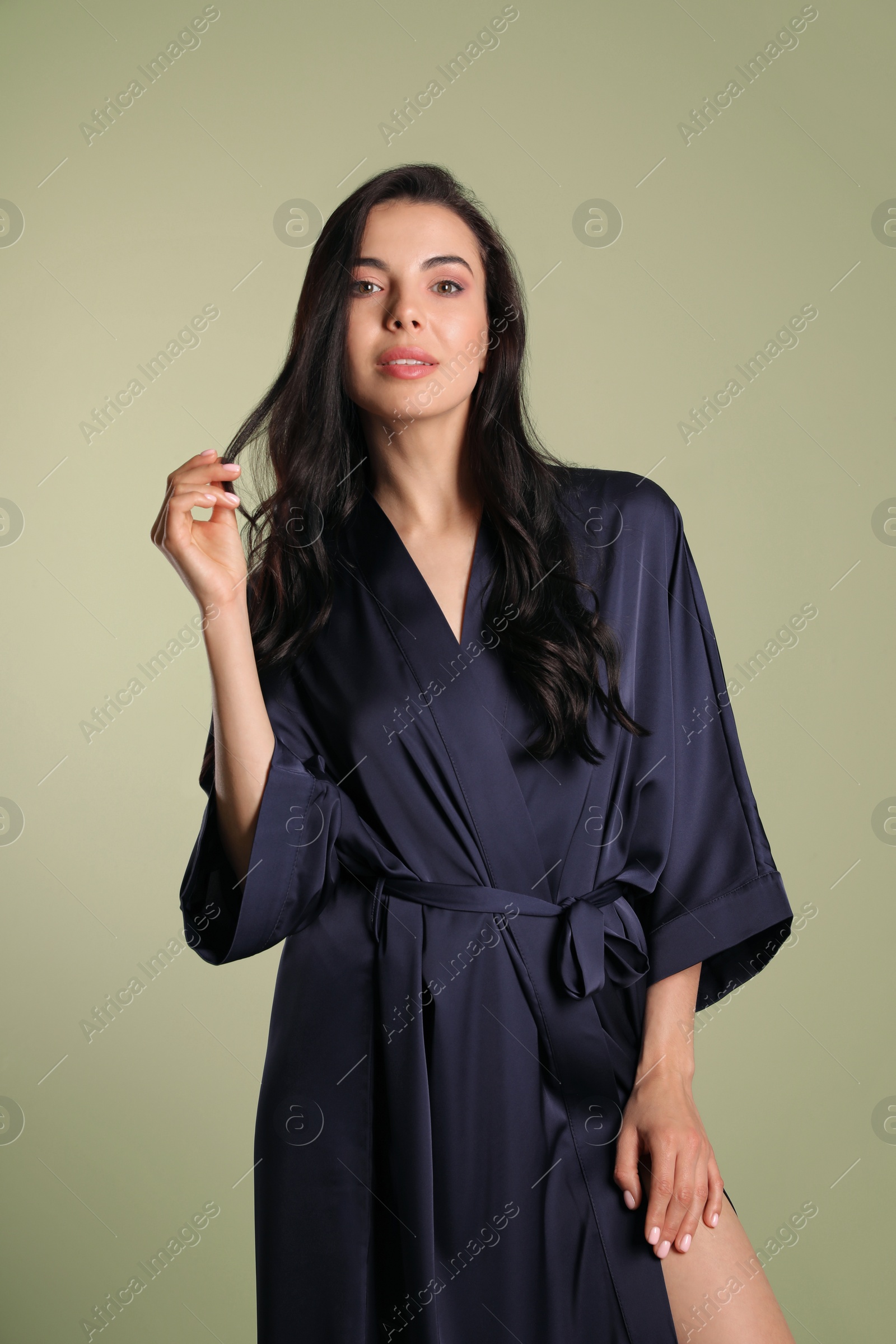 Photo of Sexy young woman in dark blue silk robe on light background