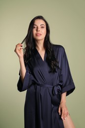 Photo of Sexy young woman in dark blue silk robe on light background