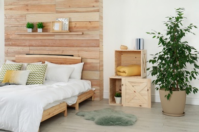 Stylish room interior with comfortable bed near wooden wall