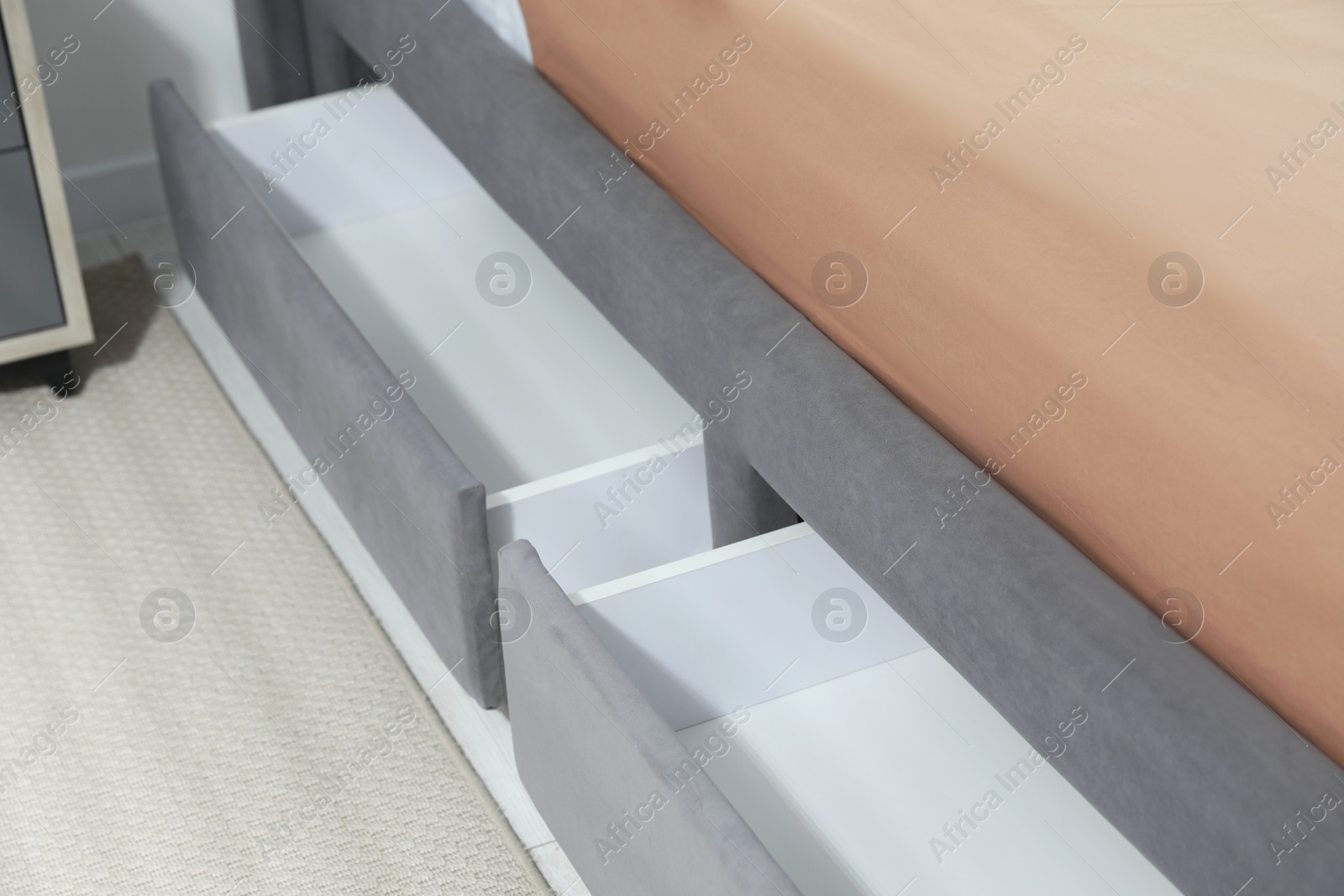 Photo of Storage drawers for bedding under modern bed in room, closeup