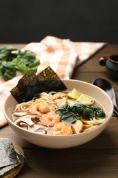 Photo of Delicious ramen with shrimps and mushrooms in bowl on wooden table. Noodle soup