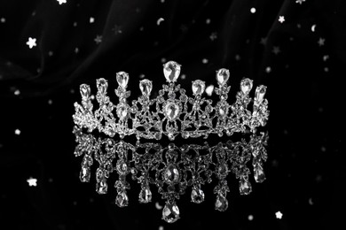 Photo of Beautiful silver tiara with diamonds on dark mirror surface