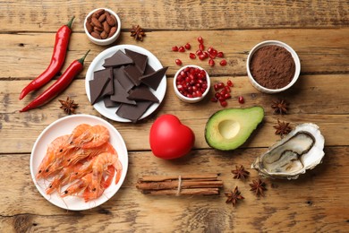 Photo of Natural aphrodisiac. Different food products and heart model on wooden table, flat lay