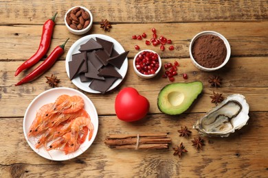 Natural aphrodisiac. Different food products and heart model on wooden table, flat lay