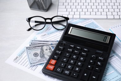Photo of Tax accounting. Calculator, documents, money and glasses on light grey table