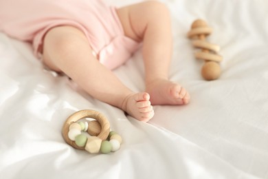 Photo of Cute baby and rattle toys on sheets, closeup