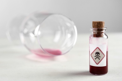 Photo of Vial of poison and partially emptied glass on light background