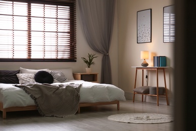 Modern room interior with comfortable double bed and window blinds