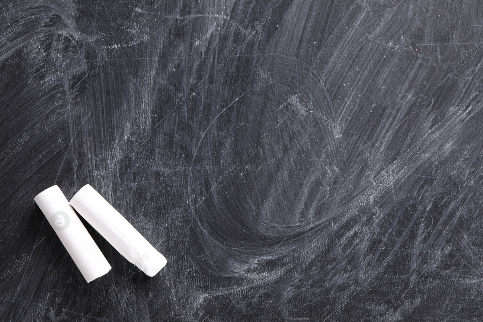 Photo of Pieces of white chalk on blackboard, flat lay. Space for text