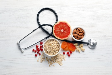 Photo of Heart-healthy products and stethoscope on wooden background, flat lay
