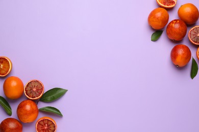 Photo of Many ripe sicilian oranges and leaves on violet background, flat lay. Space for text