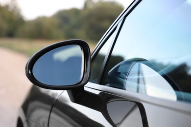 Photo of Side view mirror of modern car on blurred background, closeup