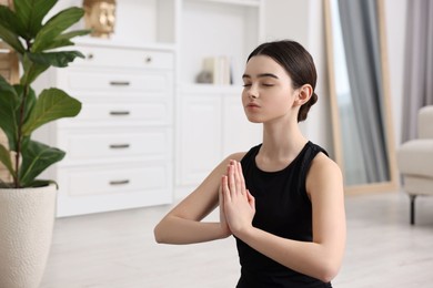 Beautiful girl meditating at home. Practicing yoga