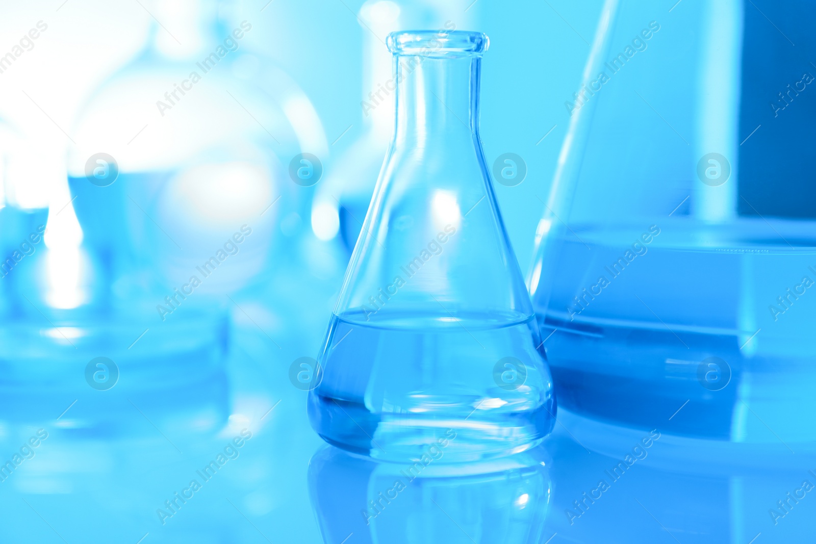 Photo of Laboratory glassware with liquid on table. Space for text