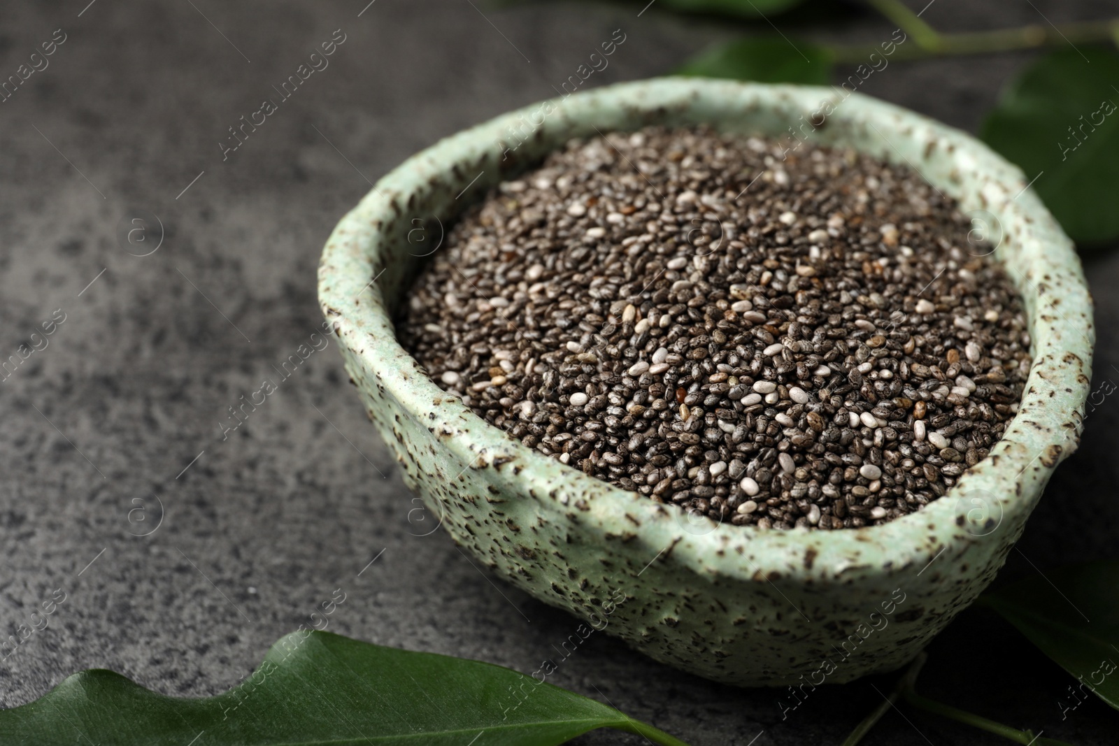 Photo of Bowl with chia seeds on grey table, closeup
