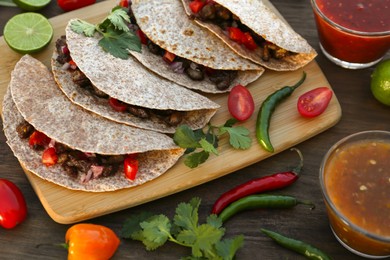 Photo of Delicious tacos with meat and vegetables on wooden table