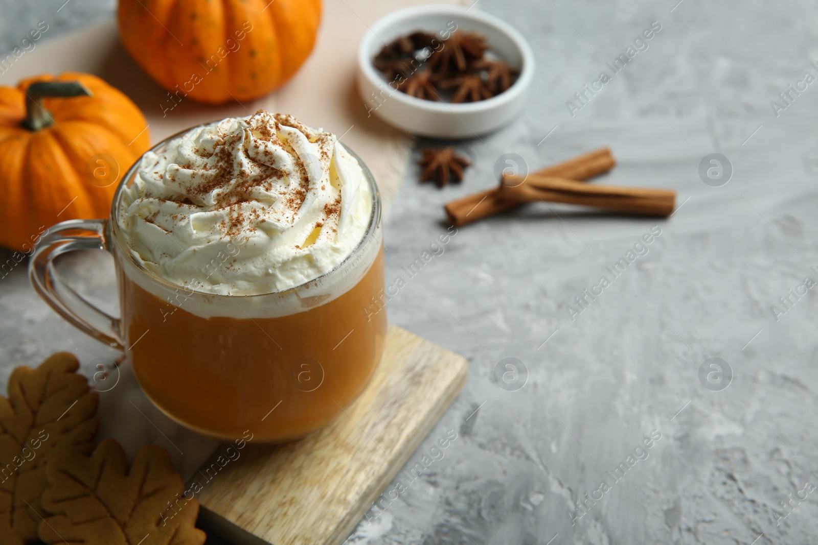 Photo of Cup of pumpkin spice latte with whipped cream on light grey table, closeup. Space for text