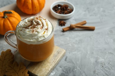 Photo of Cup of pumpkin spice latte with whipped cream on light grey table, closeup. Space for text