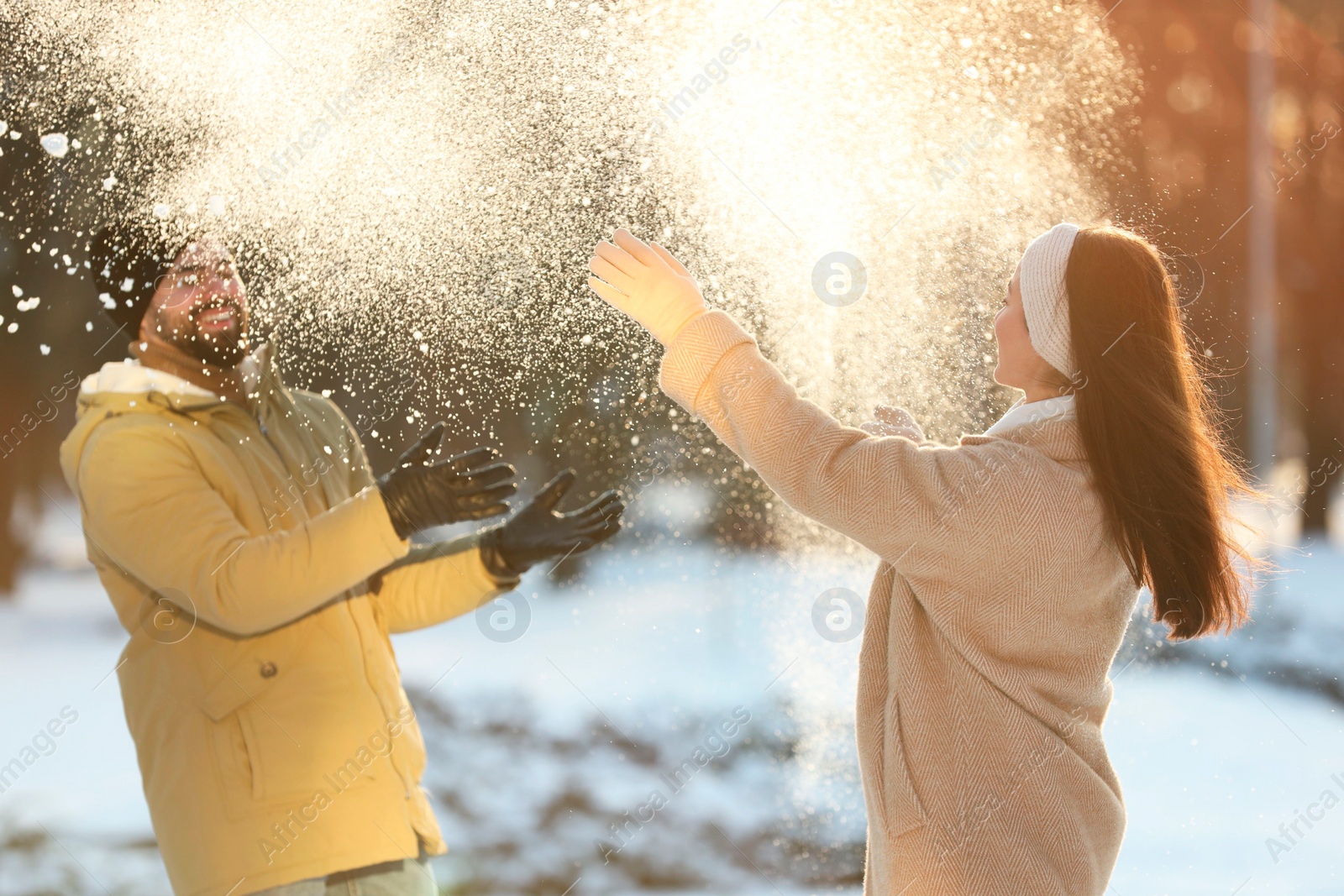 Photo of Happy couple playing snowballs on winter day outdoors